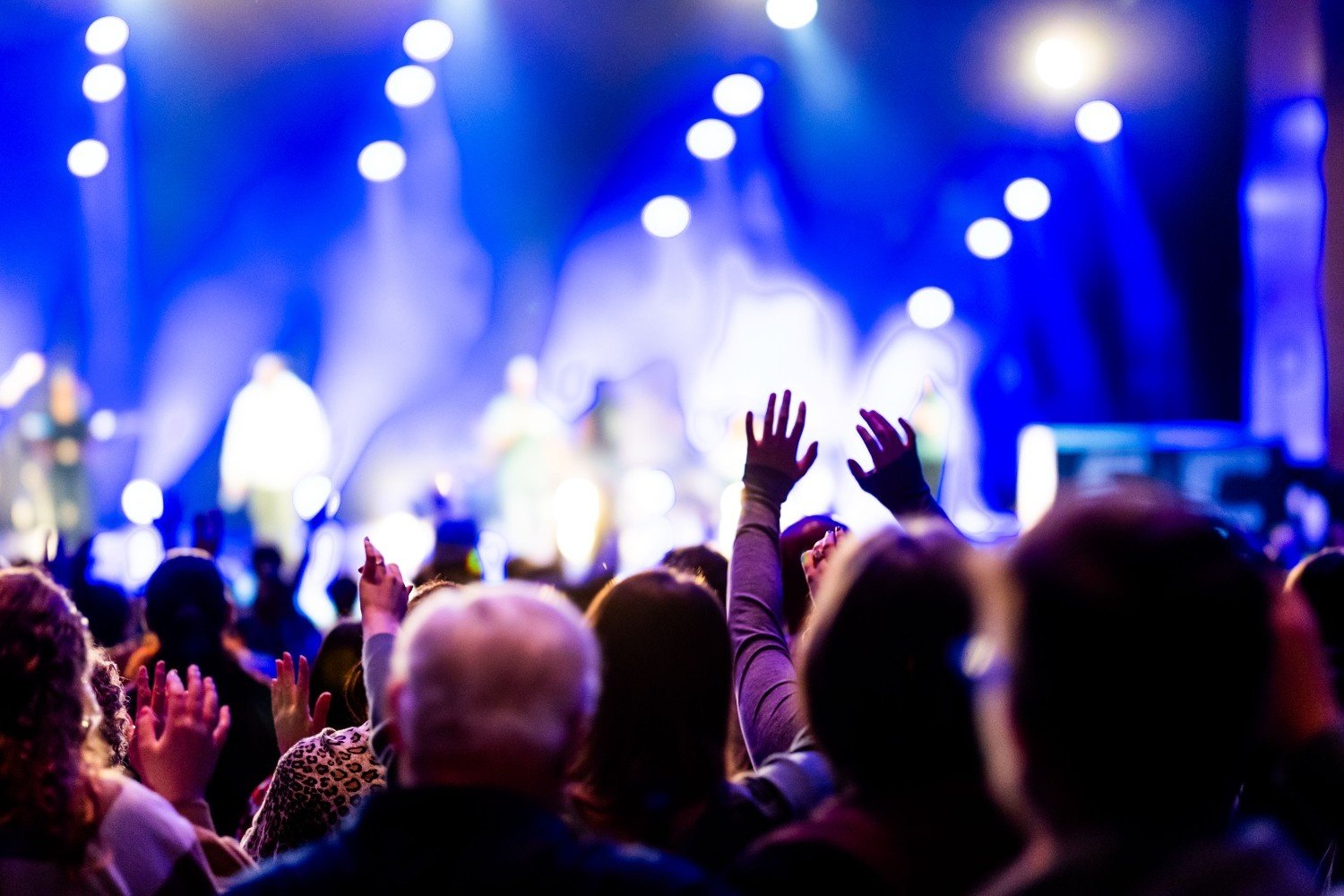 Congregation worshipping under blue stage lights